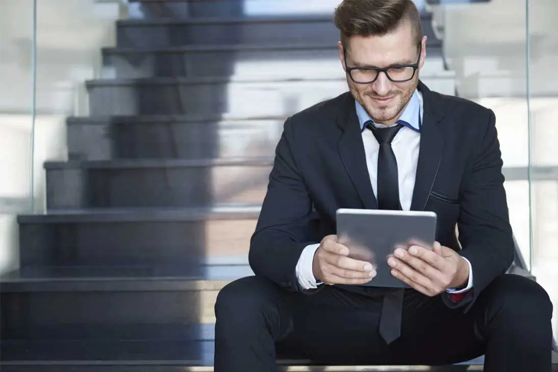 Vendedor profesional en traje utilizando una tablet para gestionar comunicaciones cloud en movilidad