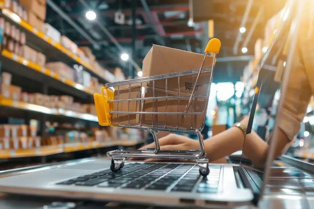 Mini carrito de la compra con una caja sobre un ordenador portátil, representando el comercio electrónico para empresas y la digitalización de pymes