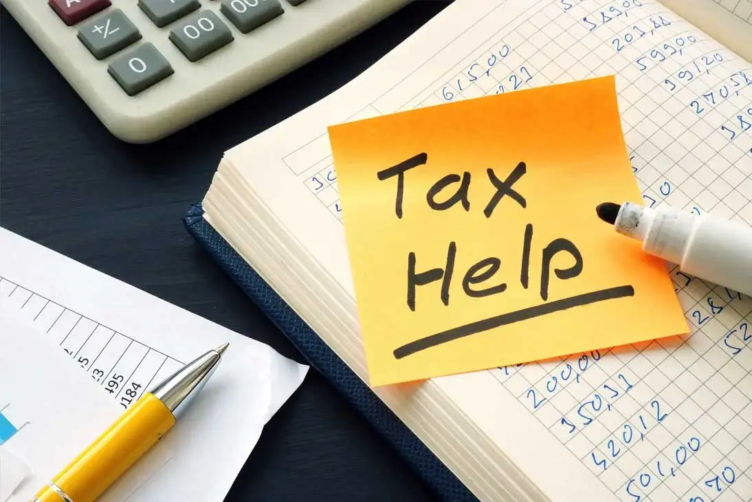 Cuaderno con apuntes contables, calculadora y una nota de ayuda fiscal que representa la adaptación al nuevo software VeriFactu