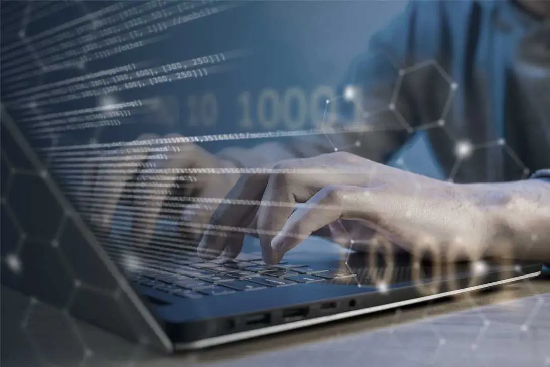Manos tecleando en un ordenador portátil con líneas de código superpuestas, representando el soporte técnico y mantenimiento ERP empresarial