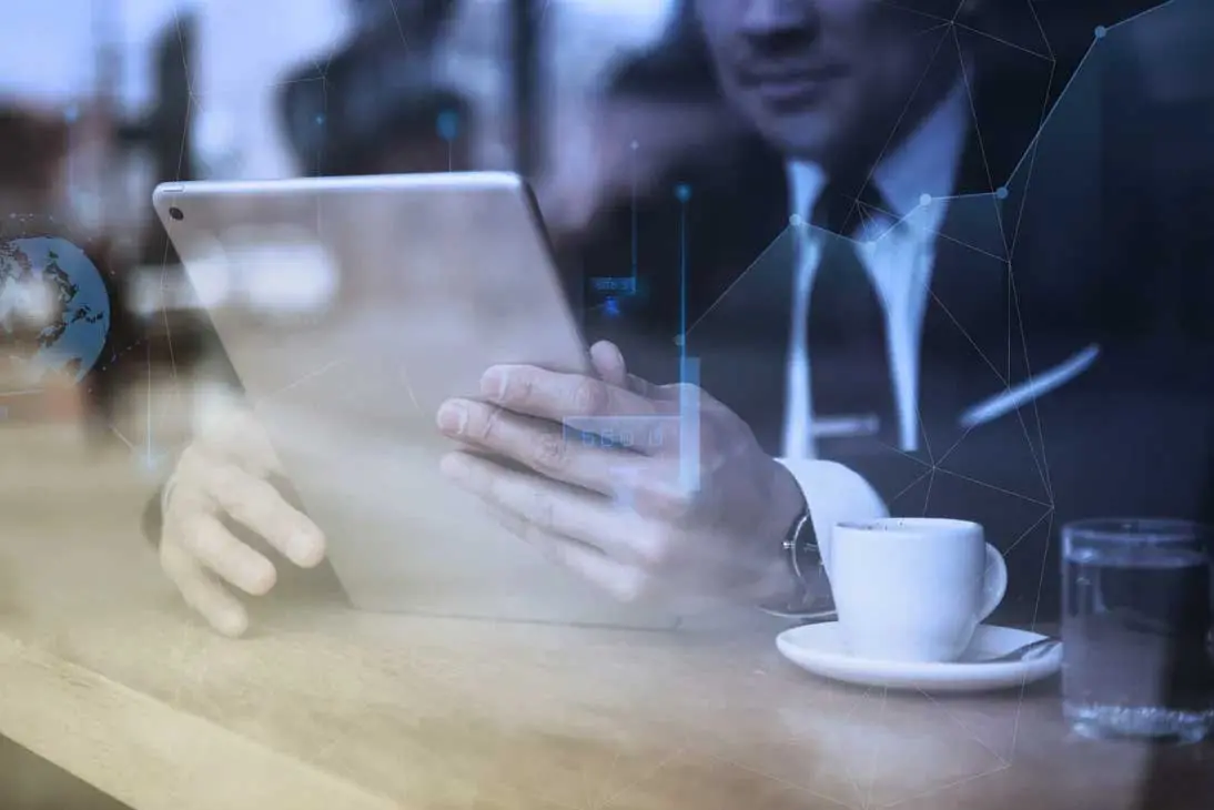 Primer plano de un ejecutivo usando una tablet con gráficos digitales de redes conectadas, ilustrando la transformación tecnológica de las empresas